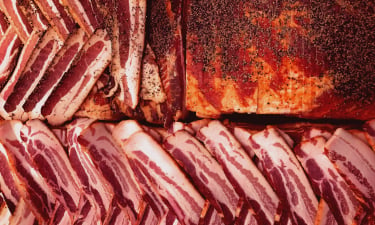 large neat rows of bacon being cut from a carcass.