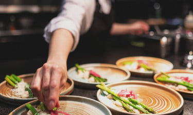 A chef plating food in the kitchen.